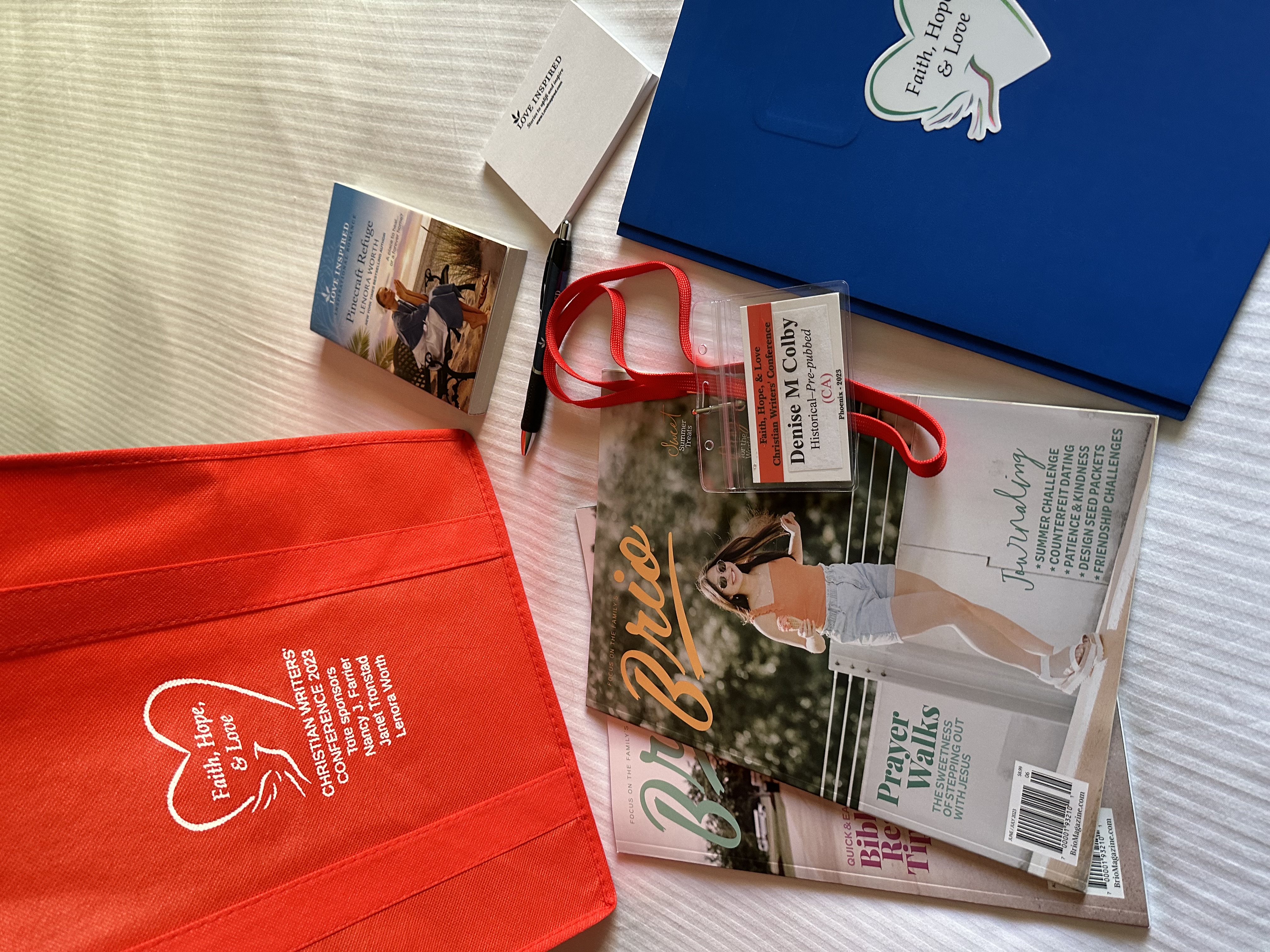 books and magazines, bag, and name tag at the Faith Hope Love Christian Writer's Conference in September 2023