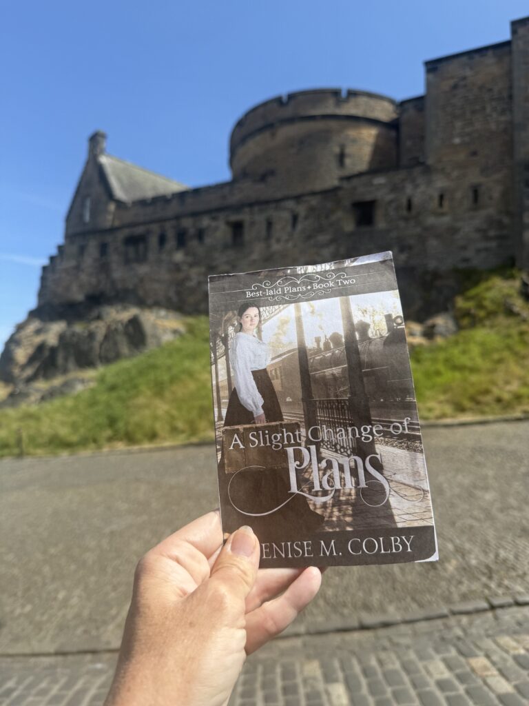 Edinburgh castle in the background with Denise M. Colby's book cover in front for book release